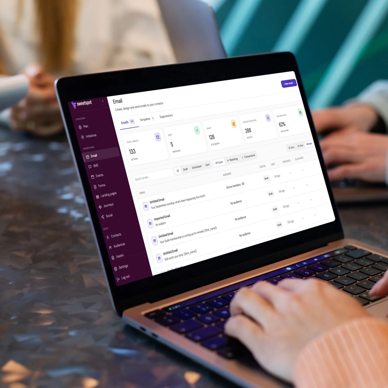 Person typing on a laptop showing the Sweetspot Email dashboard with email stats and a list of draft emails
